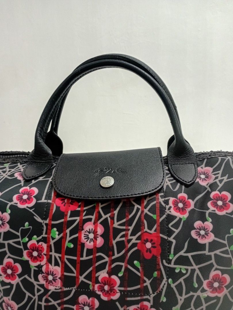 Longchamp Floral Printed Pliage MEDIUM Handbag with Shoulder Strap (Category: Luxury Bags & Wallets) located in Manila. Submitted by eriiicaspage (Listing ID 1433888964, Image 3). Description: PreOwned Lightly Used Longchamp handbag with a striking floral pattern on a black background. - Features a classic top handle and a detachable shoulder strap with red, white, and green stripes. - Secure flap closure with a snap and a silver-tone zipper. - I