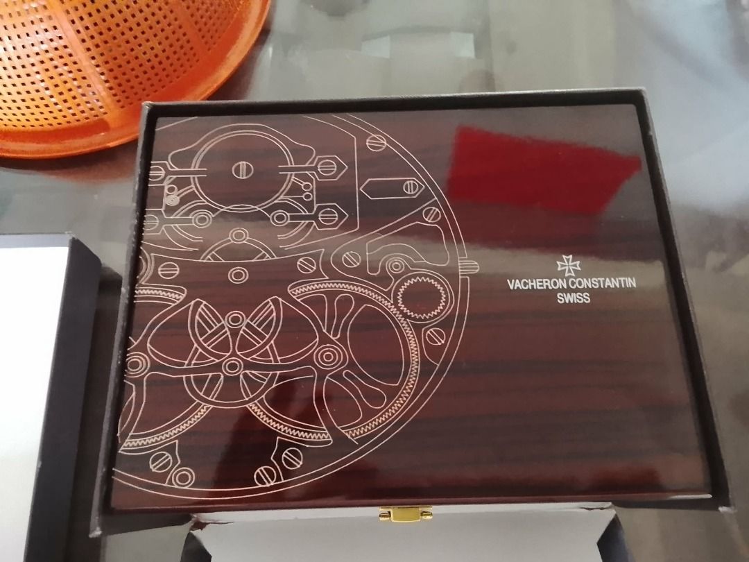 Vacheron Constantin Watch Box (Category: Luxury Watches) located in Bauang. Submitted by missisv (Listing ID 1433893730, Image 3). Description: - Authentic Vacheron Constantin watch box - Dark wood finish - Intricate gear design on lid - Features Vacheron Constantin logo and "Swiss" text Brand: Vacheron Constantin Collection: Overseas Model Reference: Commonly 47040/000A-9008 or 5520V/210A-B148 (depending on exact version) Case Material: Stainles