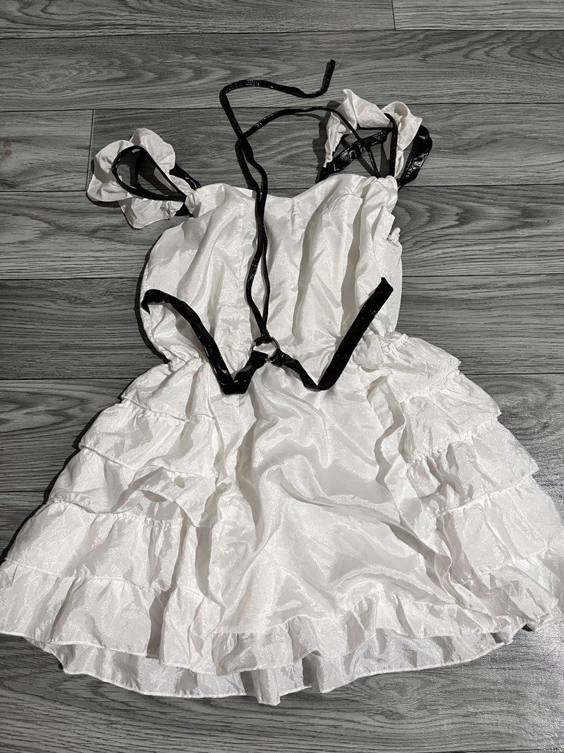 White Ruffled Dress with Black Accents (Category: Dresses) located in Pasig City. Submitted by anya2000 (Listing ID 1433903076, Image 1). Description: - White dress with a playful ruffled skirt. - Contrasting black accents on straps, neckline, and sleeves. - Unique design with black detailing. - Comfortable fit with an elasticated back. - Made from a lightweight, potentially sheer fabric..