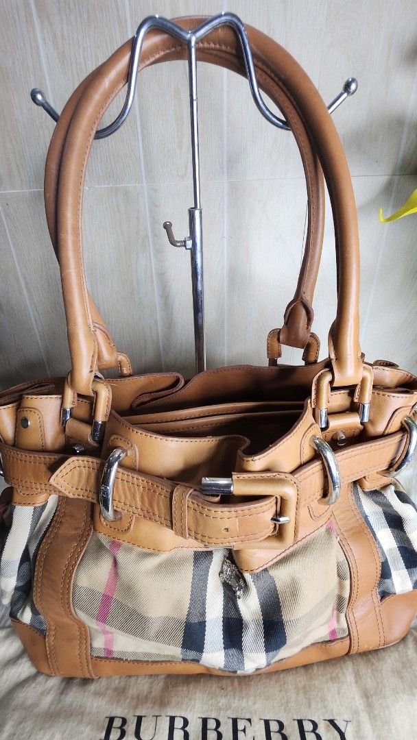 Burberry Leather Handbag (Category: Luxury Bags & Wallets) located in Cavite. Submitted by geturs (Listing ID 1433978823, Image 2). Description: - Authentic Burberry handbag - Tan leather exterior - Classic Burberry check interior - Includes dust bag - Structured design with multiple compartments - Secure buckle closures - Sturdy handles - Metal hardware - Perfect for everyday use NOTE: bag is slightly heavy due to leather and buckles.