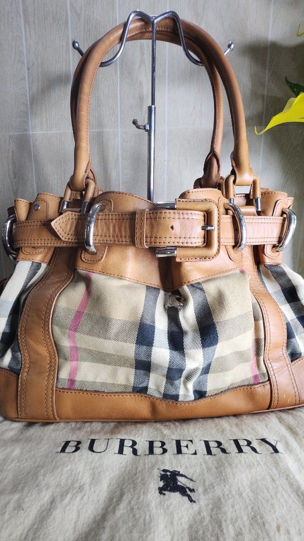 Burberry Leather Handbag (Category: Luxury Bags & Wallets) located in Cavite. Submitted by geturs (Listing ID 1433978823, Image 1). Description: - Authentic Burberry handbag - Tan leather exterior - Classic Burberry check interior - Includes dust bag - Structured design with multiple compartments - Secure buckle closures - Sturdy handles - Metal hardware - Perfect for everyday use NOTE: bag is slightly heavy due to leather and buckles.