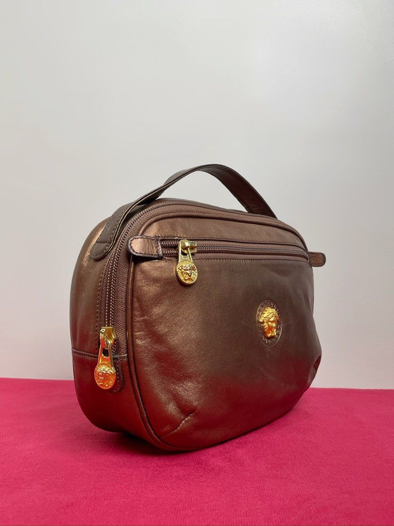 Gianni Versace Bronze Handbag (Category: Luxury Bags & Wallets) located in Manila. Submitted by relovedclub2024 (Listing ID 1434011528, Image 2). Description: - Gianni Versace handbag - Bronze color - Top handle - Multiple zippered compartments - Gold-toned Medusa head hardware - Brown fabric interior - Gianni Versace label - Made in Italy.