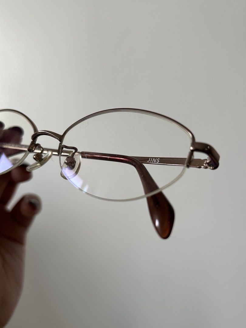 JINS rimless Eyeglasses Bayonetta style (Category: Sunglasses & Eyewear) located in Makati City. Submitted by catalogue.ph (Listing ID 1434173464, Image 2). Description: - Brand: JINS - Frame: Gold-colored - Design: Semi-rimless - Lenses: Oval - Temples: Brown - Suitable for everyday wear.