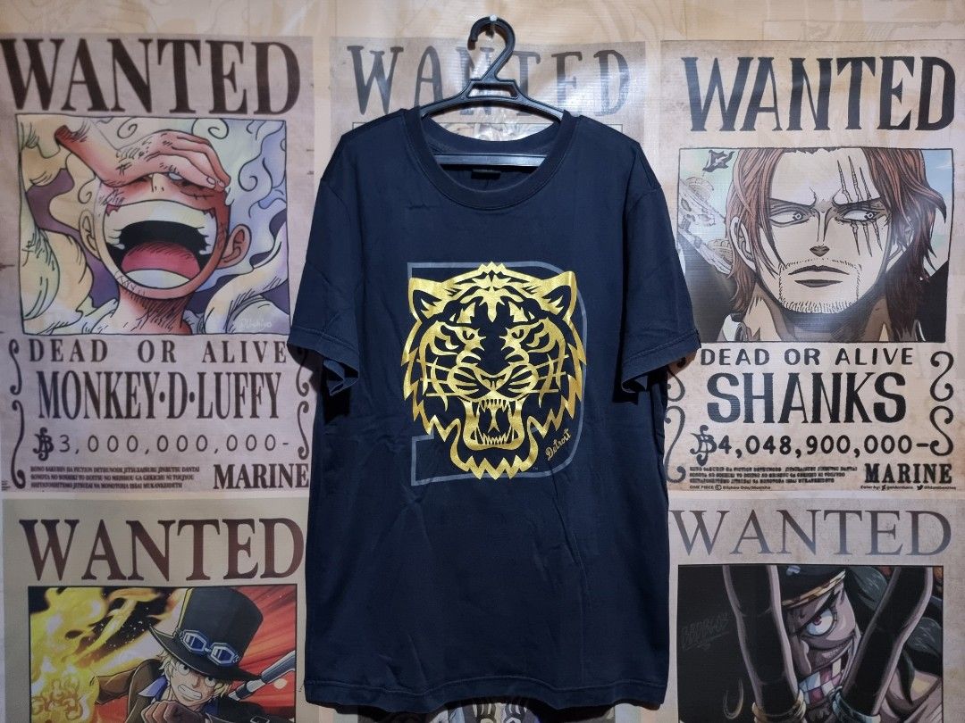 MLB Detroit Tigers Graphic Tee - Large (Category: Tshirts & Polo Shirts ) located in Imus. Submitted by aim_for_less (Listing ID 1434117562, Image 1). Description: MLB Detroit Tigers Graphic Tee Features a striking gold tiger design on a navy blue background. It has a crew neck and short sleeves. The tag indicates it is a size Large (175/92A). Made by MLB (Major League Baseball) -DIMES: 21" X 29" - COLOR RATE: 9.7/10 - NO ISSUE - VERY GOOD CONDIT