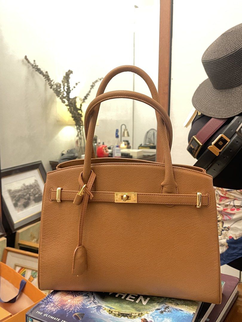 Tan Satchel Handbag with Gold Hardware (Category: Luxury Bags & Wallets) located in Marilao. Submitted by wardrovearchives (Listing ID 1434054402, Image 1). Description: - Tan satchel handbag - Structured design - Gold-tone hardware - Top handle - Secure clasp closure - Textured material (Italian leather) - Includes matching lock and key -Made in Italy.