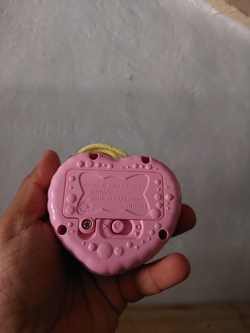 Bandai Heart-Shaped Toy (Category: Kids Toys) located in Quezon City. Submitted by jpnvintageonline (Listing ID 1434213794, Image 2). Description: - Heart-shaped toy with gold frame - Adorned with colorful gems and a star design - Pink back with battery compartment - Includes a yellow string - Made in Thailand by Bandai.