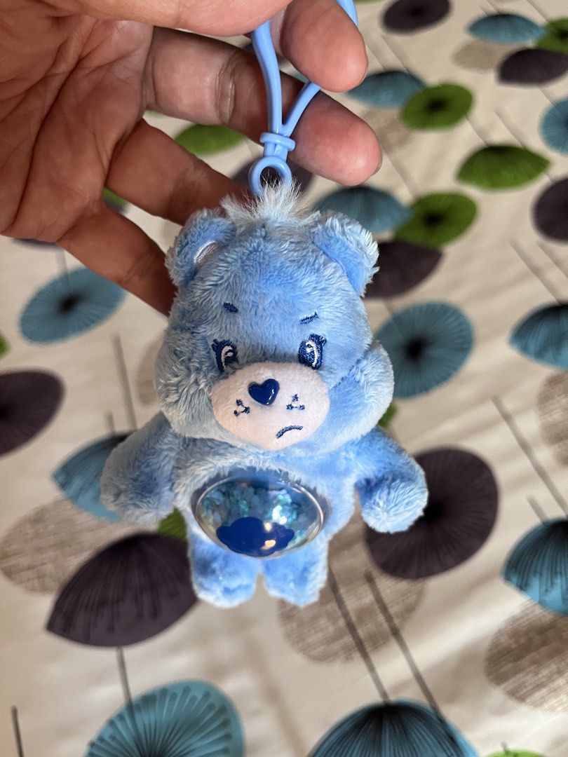Care Bears Grumpy Bear Keychain (Category: Plushies & Soft Toys) located in Cainta. Submitted by llsamson2000 (Listing ID 1434183267, Image 2). Description: - Cute Grumpy Bear keychain - Features a blue plush design - Heart-shaped belly - Includes a blue clip for easy attachment - Small cloud design inside the belly - From POP MART.
