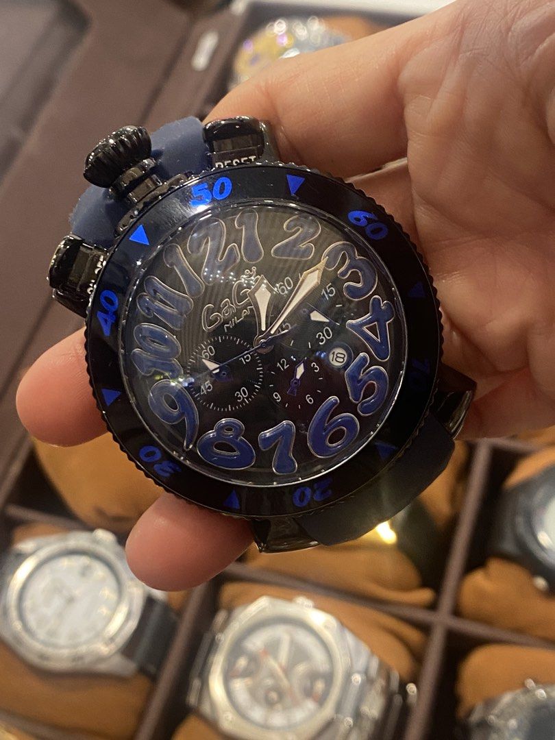 GaGa Milano Watch (Category: Luxury Watches) located in Manila. Submitted by roseluxuryitems (Listing ID 1434223407, Image 2). Description: - GaGa Milano watch with a unique design. - Black dial with large, blue numerals. - Blue rubber strap. - Black bezel with blue markings. - Multiple sub-dials and pushers. - Water-resistant to 100M. - Marked "GaGa Milano" and "100M WATER ITALY" on the back. - Made in Italy..