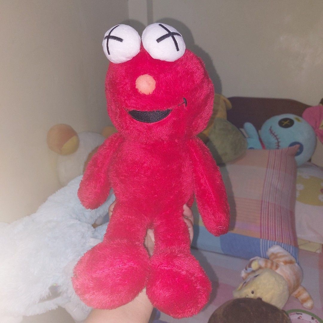 KAWS Plush Toys (Category: Plushies & Soft Toys) located in Mandaluyong City. Submitted by 13thsilverrabbit (Listing ID 1434189900, Image 2). Description: Collection of KAWS plush toys in various colors. Includes blue, black, white, gray, and brown figures. Also includes a red Elmo-like plush toy with X eyes. These plush toys are soft and cuddly, perfect for display or as a gift..