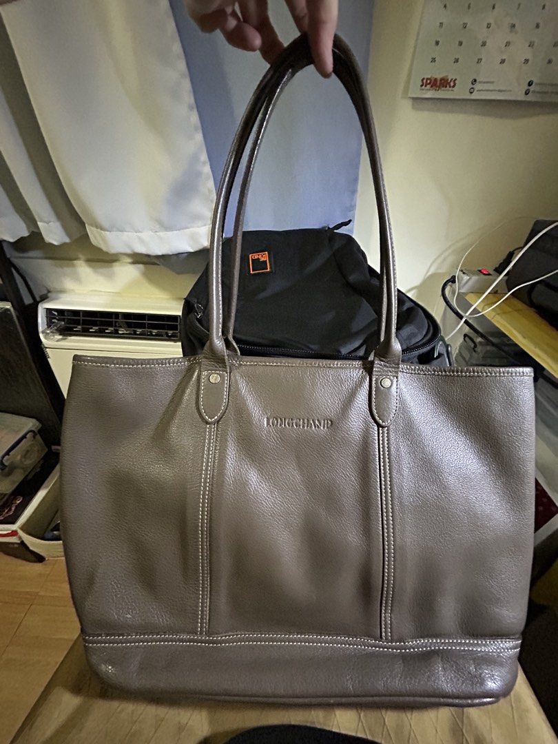RARE Longchamp Leather Tote Bag (Category: Luxury Bags & Wallets) located in Manila. Submitted by victoria_victorino (Listing ID 1434339468, Image 2). Description: Longchamp leather tote bag. Features a spacious main compartment and two top handles. The bag has a neutral color with visible stitching details. Pink interior lining. 33 x 26 cm The Longchamp logo is embossed and displayed on the front. Bought in Poland, well loved..