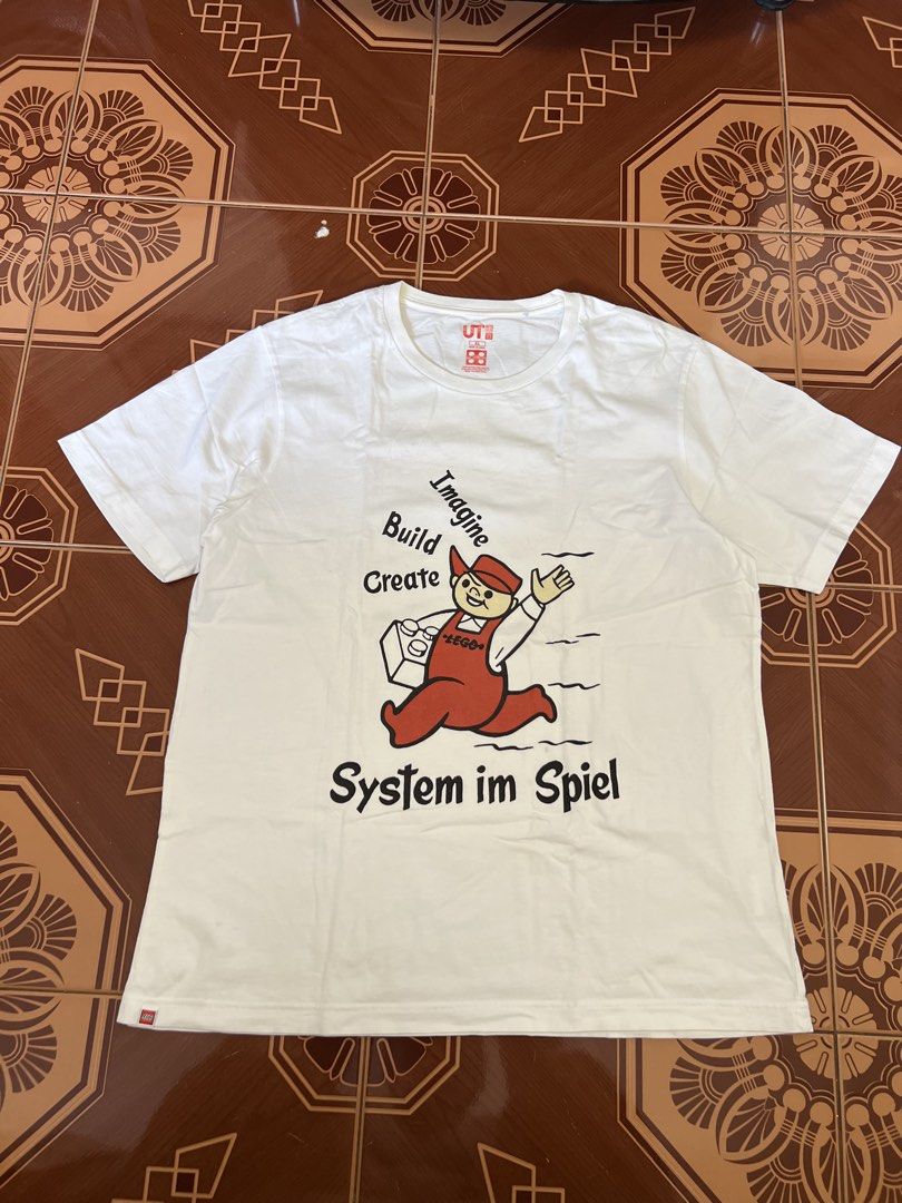 Uniqlo UT LEGO Graphic Tee (Category: Tshirts & Polo Shirts ) located in Manila. Submitted by mark_decluttering (Listing ID 1434215816, Image 1). Description: - White Uniqlo UT t-shirt - Features a LEGO graphic - Includes the words "Imagine, Build, Create, System im Spiel" - Design includes a LEGO character - Short sleeves - Crew neck - Uniqlo UT logo on collar.