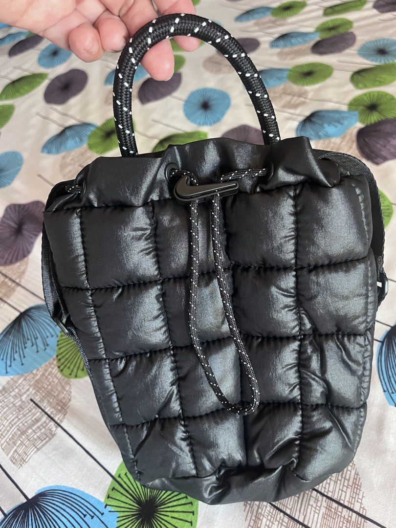 Black Padded Bucket Bag with Drawstring (Category: Shoulder Bags) located in Cainta. Submitted by llsamson2000 (Listing ID 1434390380, Image 2). Description: - Black quilted bucket bag - Drawstring closure - Top handle with rope-like texture - Detachable shoulder strap - Shiny, padded material - Nike logo detail.