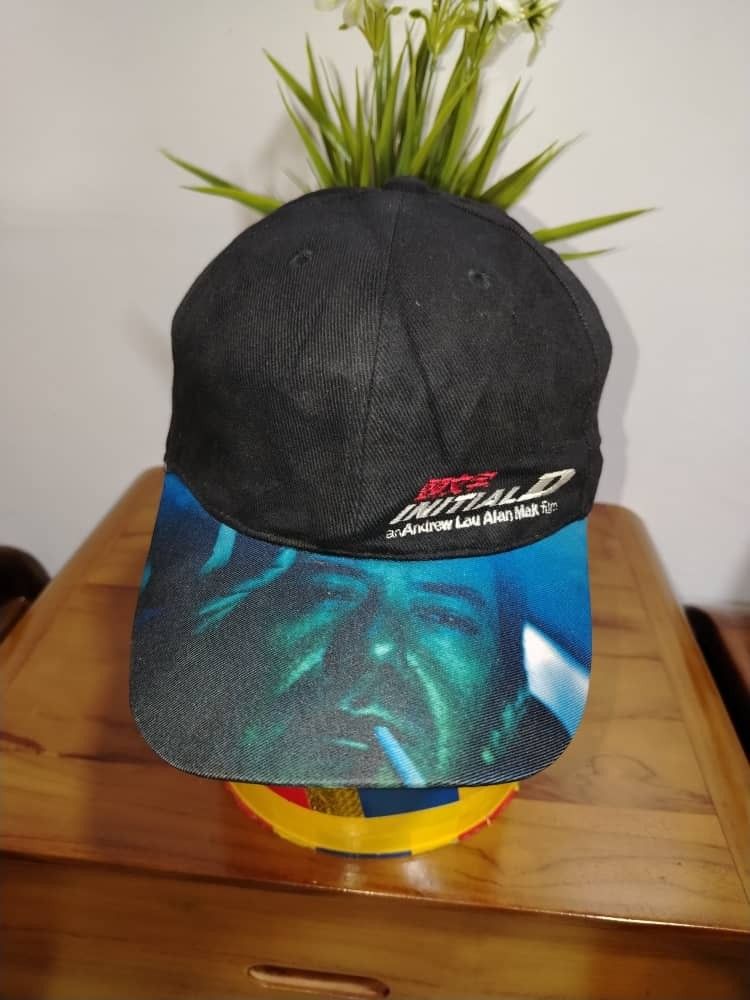Initial D Cap (Category: Cap & Hats) located in Tawau. Submitted by Rombengan_Bundle (Listing ID 1434552690, Image 2). Description: - Initial D cap - Black crown, blue brim - Features Initial D logo and graphic - Durable fabric - Adjustable strap.