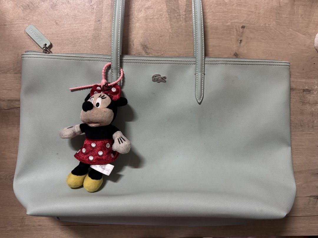 Lacoste Tote Bag with Minnie Mouse Charm (Category: Tote Bags) located in Taguig. Submitted by suzzsy (Listing ID 1434511783, Image 1). Description: - Light blue green Lacoste tote bag - Zipper closure - Two handles - Includes Minnie Mouse plush charm - Features Lacoste logo - Made of textured material.