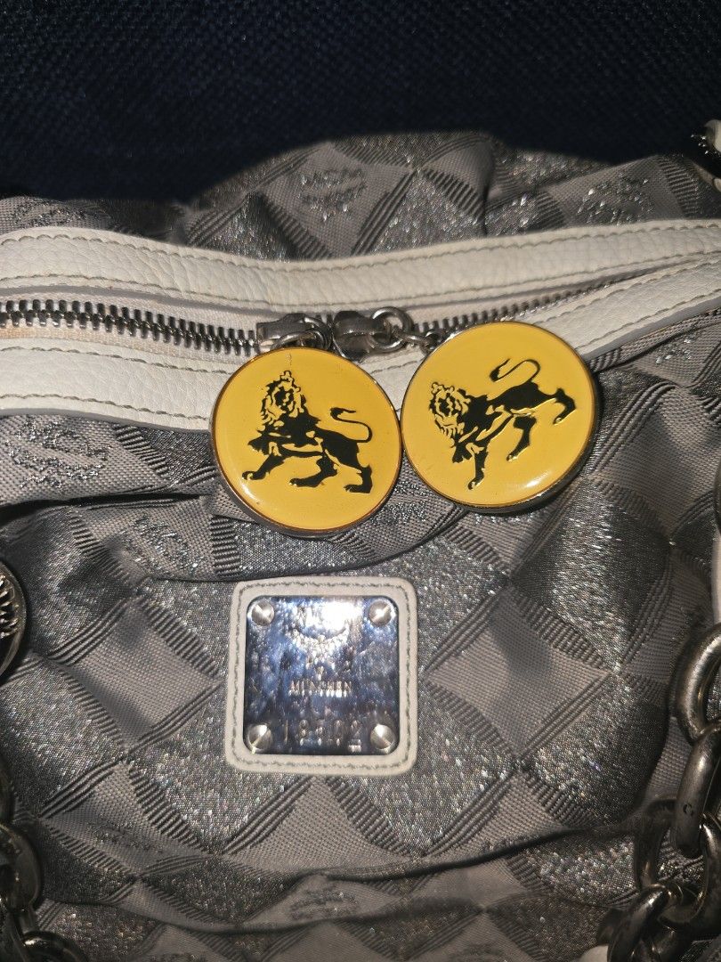 MCM Silver Handbag with Chain Detail (Category: Luxury Bags & Wallets) located in Manila. Submitted by heartless724 (Listing ID 1434524050, Image 2). Description: - Stylish MCM handbag - Silver with white accents - Diamond pattern design - Chain details - White leather base - Zipper closure - Two yellow circular charms - Silver hardware - Structured shape.