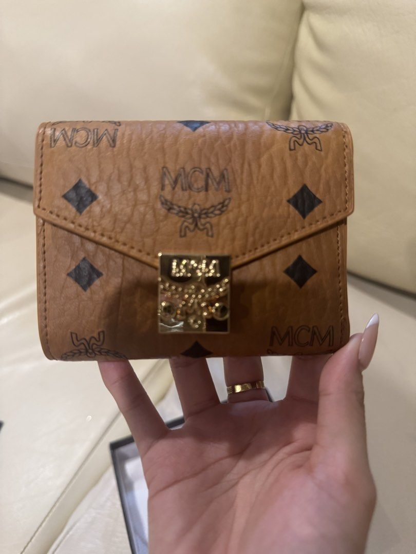 MCM Trifold Wallet (Category: Luxury Bags & Wallets) located in Las Pinas. Submitted by sircsarchives (Listing ID 1434502813, Image 2). Description: Authentic MCM trifold wallet. Features the iconic MCM logo pattern and a gold-tone clasp. Includes a zippered compartment and a protective dust bag. The wallet has a compact design, suitable for everyday use..