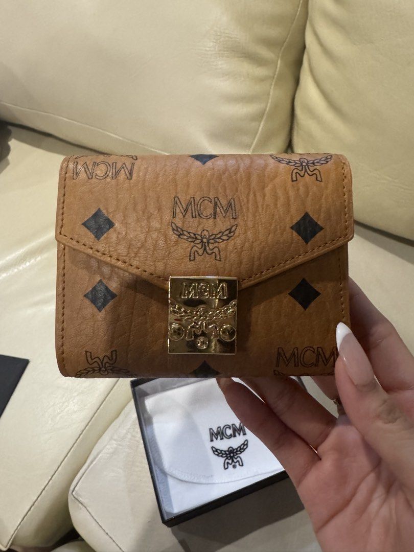 MCM Trifold Wallet (Category: Luxury Bags & Wallets) located in Las Pinas. Submitted by sircsarchives (Listing ID 1434502813, Image 1). Description: Authentic MCM trifold wallet. Features the iconic MCM logo pattern and a gold-tone clasp. Includes a zippered compartment and a protective dust bag. The wallet has a compact design, suitable for everyday use..