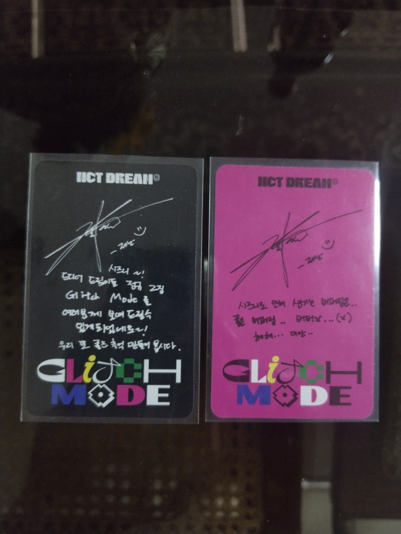 NCT Dream Glitch Mode Jeno Photocards (Category: K-Wave Merchandise) located in Manila. Submitted by tyrapple (Listing ID 1434454305, Image 2). Description: - 199 each Jeno photocards from NCT Dream's Glitch Mode album - Features: - Jeno with pink hair and chain - Jeno with a scarf - Backs of photocards have signatures and Korean text - Both photocards are in protective sleeves.