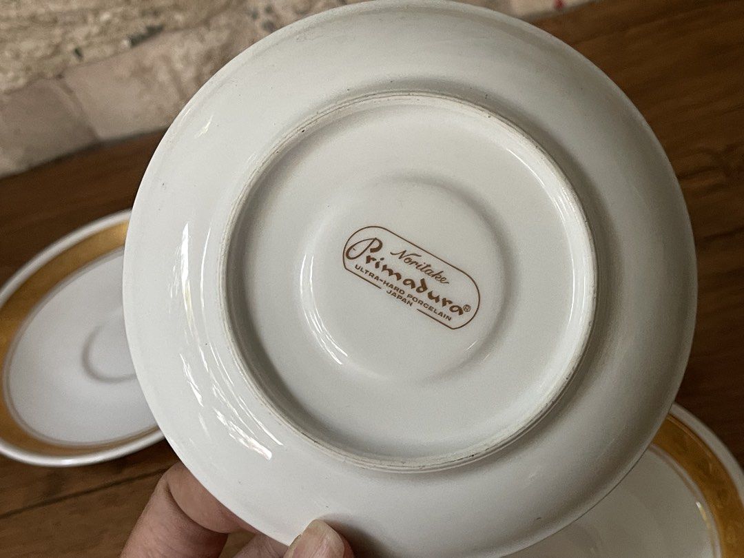 Noritake Primadura Saucers (Category: Coffee & Tea Tableware) located in San Fernando. Submitted by japansurpluselyu (Listing ID 1434583272, Image 3). Description: - Set of four Noritake Primadura saucers - Features a white base - Elegant gold rim and accents - Marked "Ultra-Hard Porcelain Japan" - Perfect for tea or coffee service.