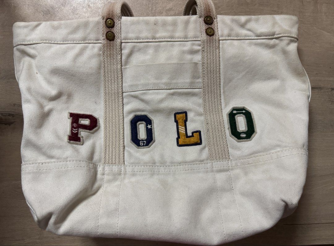 Polo Ralph Lauren Canvas Tote Bag (Category: Tote Bags) located in Taguig. Submitted by suzzsy (Listing ID 1434511676, Image 1). Description: - Polo Ralph Lauren tote bag - Features a colorful logo patch - Cream canvas exterior - Sturdy handles - Small front pocket - Good size for everyday use - Shows some signs of wear.
