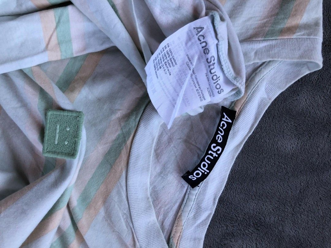 Acne Studios Striped T-shirt (Category: Tshirts & Polo Shirts ) located in Manila. Submitted by niggzreyno51476 (Listing ID 1434642667, Image 3). Description: - Acne Studios striped t-shirt - Crew neck design - Features a small square face logo patch - Horizontal stripes in white, green, and orange - Brand label visible on the inside collar - Includes brand tag with washing instructions - New with tags.