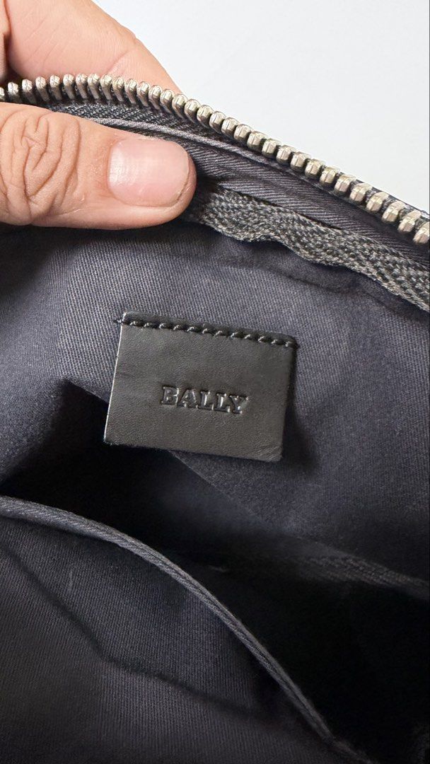 Bally Black Clutch Bag (Category: Luxury Bags & Wallets) located in Alfonso. Submitted by jbcamet (Listing ID 1434732916, Image 2). Description: Black clutch bag by Bally. Features a zip closure and a wrist strap. The interior includes a small pocket and a brand label. The bag is made in Spain. The exterior has a subtle pattern. The zipper has a Bally logo on the pull..