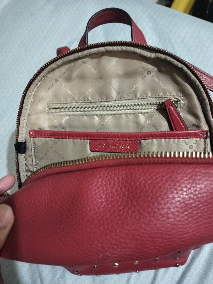 Michael Kors Red Studded Backpack (Category: Backpacks) located in Laoag. Submitted by loml_e.zt (Listing ID 1434802674, Image 3). Description: - Authentic Michael Kors backpack - Vibrant red color - Gold-colored stud details on front pocket - Top handle and adjustable straps - Zipper closure - Main compartment and interior pocket - Michael Kors logo visible.