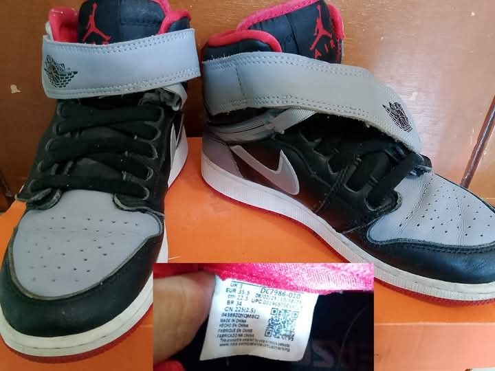 Air Jordan 1 Mid BG Black Grey Red (Category: Sneakers) located in Batangas. Submitted by edenelektra (Listing ID 1434870836, Image 1). Description: - Air Jordan 1 Mid BG sneakers - Colorway: Black, Grey, and Red - Size: US 5, EUR 37.5, CM 23.5 - Features a strap with the Jordan logo - Black swoosh on the side - Box not included.