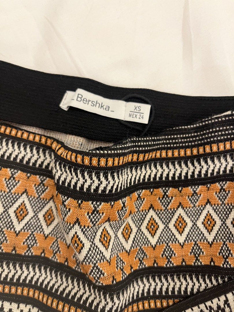 Bershka XS Skirt (Category: Skirts) located in Manila. Submitted by marianaaa0502 (Listing ID 1434927400, Image 2). Description: - Bershka skirt - Size: XS - Style: Wrap - Waistband: Black elastic - Pattern: Geometric - Colors: Black, white, and orange.