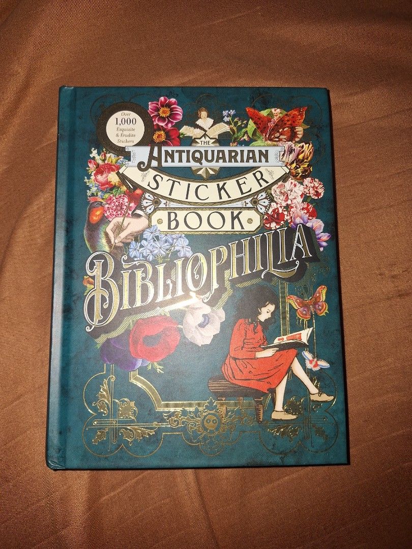 Bibliophilia Antiquarian Sticker Book (Category: Storybooks) located in Manila. Submitted by keenfish-40b7 (Listing ID 1434951643, Image 1). Description: - Vintage-style sticker book - Features illustrations of butterflies, circus performers, and whimsical characters - Teal cover with gold accents - Contains numerous sticker pages - Ideal for crafting, scrapbooking, and collecting.