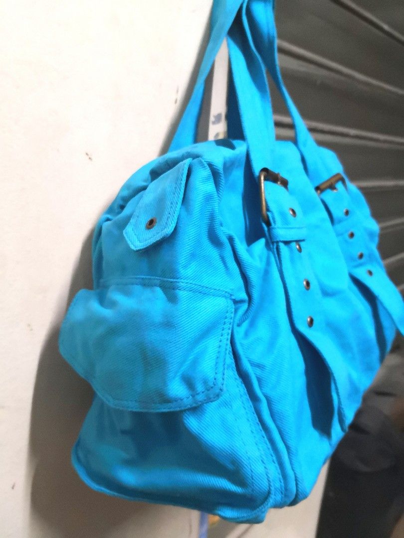 Blue Canvas Handbag with Buckle Detail (Category: Tote Bags) located in Manila. Submitted by m.curates (Listing ID 1434868496, Image 2). Description: - Blue canvas handbag - Rectangular shape - Two handles with buckle details - Two side pockets - Zippered main compartment - Colorful cartoon print lining - Dimensions: 11 inches (height) x 14 inches (length) x 6 inches (width).
