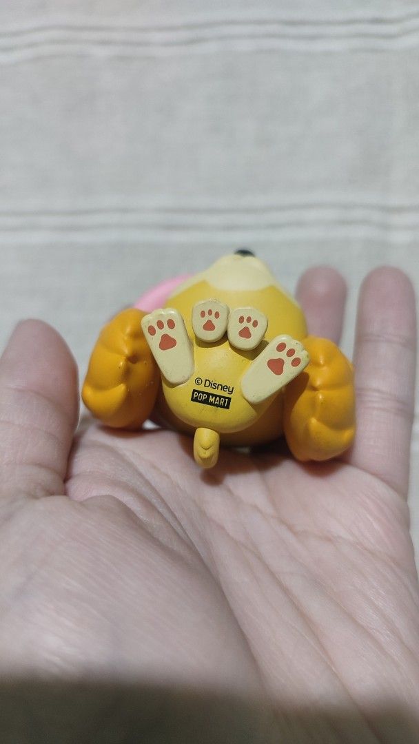 Disney POP MART Dog Figurine (Category: Designer & Blind Box Toys) located in Baguio. Submitted by lynx_. (Listing ID 1434911964, Image 2). Description: - Adorable yellow dog figurine - Features a pink hat - Sporting a blue collar - Paw prints on its feet - Marked "© Disney POP MART" - Perfect for Disney fans - Collectible item.