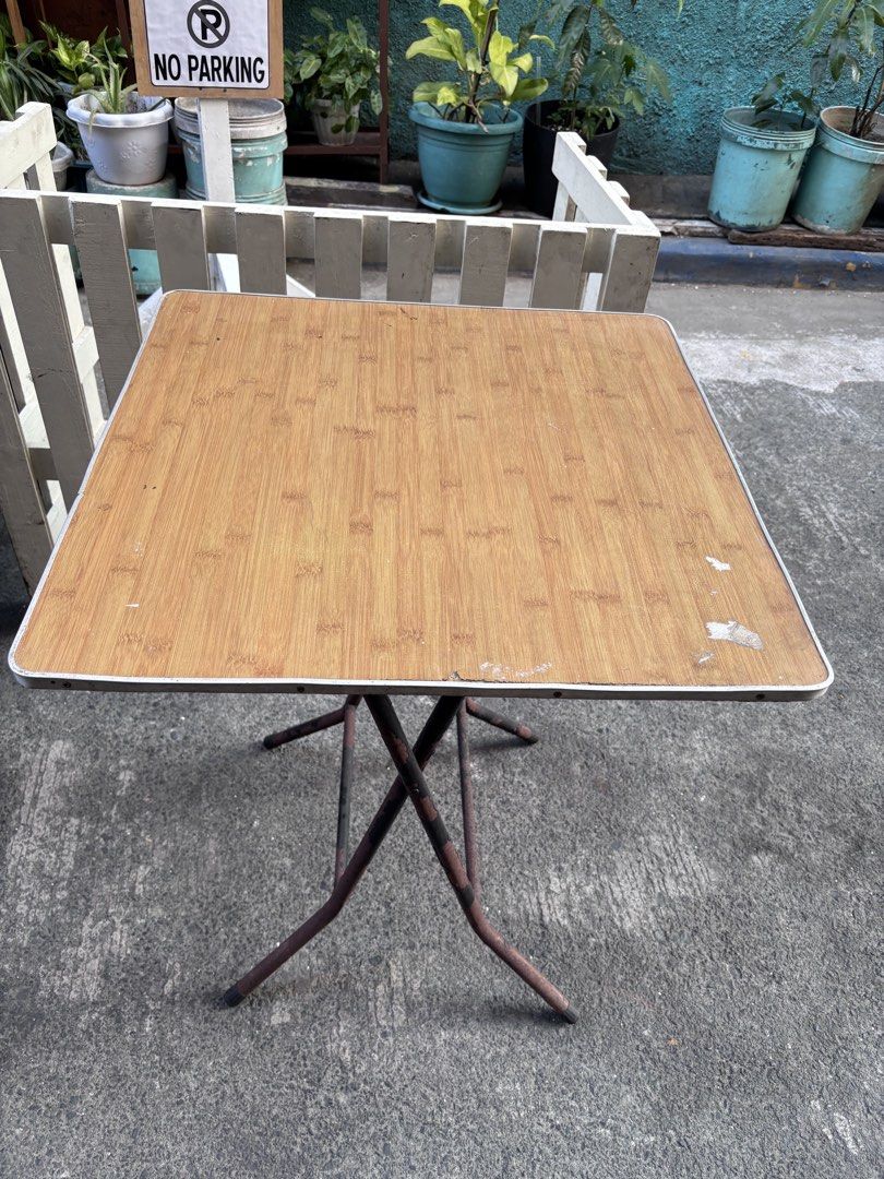 Folding Outdoor Square Table with Wooden Top (Category: Tables & Sets) located in Manila. Submitted by offtherack_mnl (Listing ID 1434869687, Image 1). Description: - Square folding table - Wooden-look top - Metal frame and legs - White trim on edges - Ideal as a side table or small dining table - Folds for convenient storage - 24” x 24” x 31”.