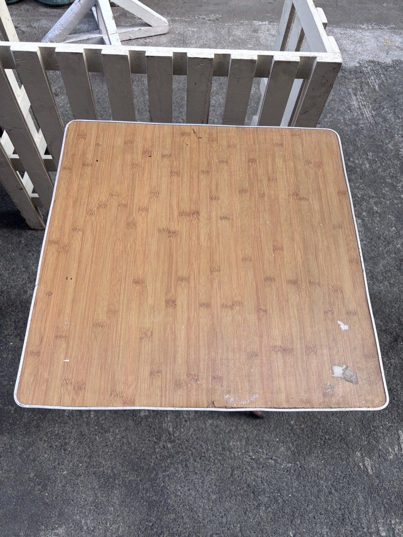 Folding Outdoor Square Table with Wooden Top (Category: Tables & Sets) located in Manila. Submitted by offtherack_mnl (Listing ID 1434869687, Image 2). Description: - Square folding table - Wooden-look top - Metal frame and legs - White trim on edges - Ideal as a side table or small dining table - Folds for convenient storage - 24” x 24” x 31”.