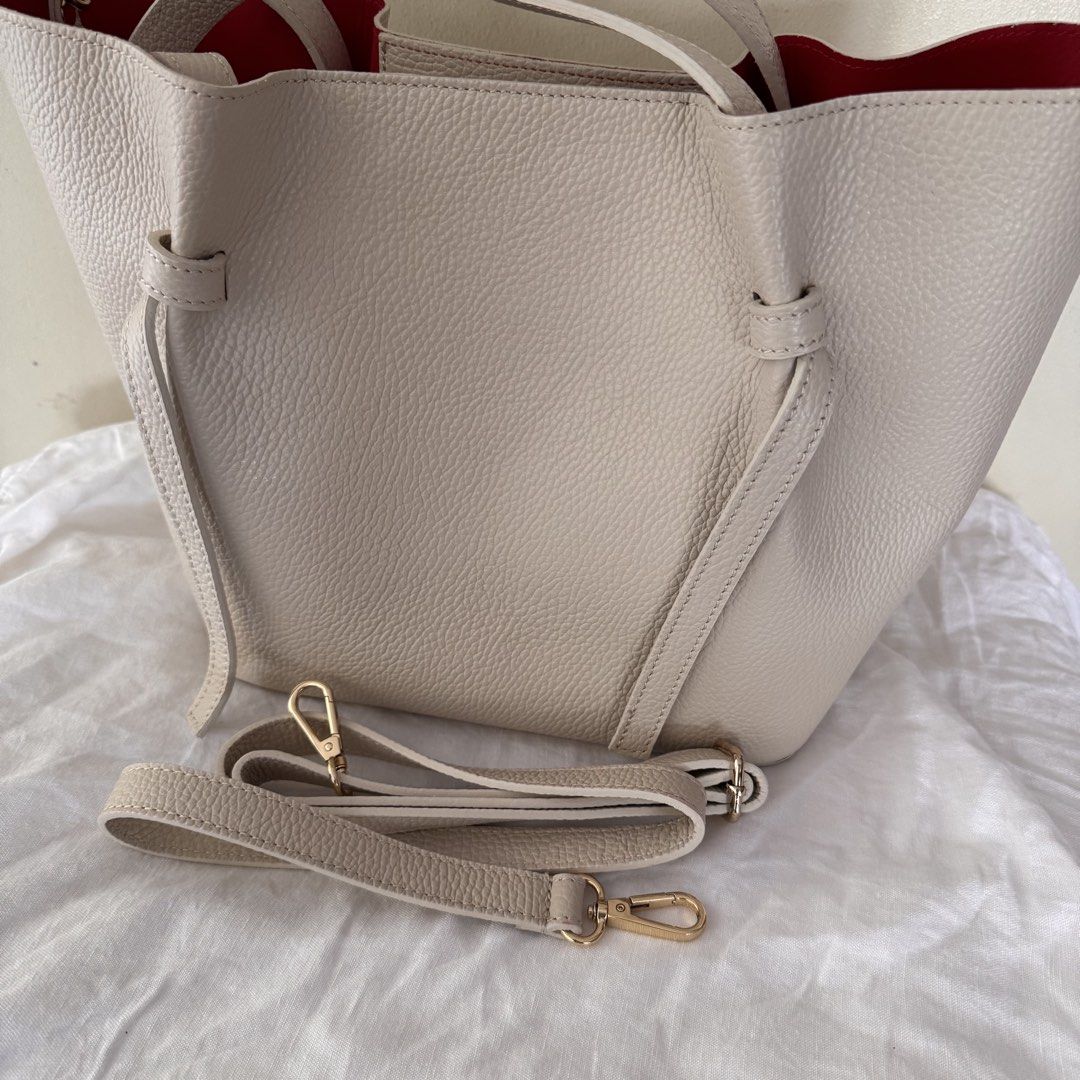 Genuine Leather Handbag with Red Interior (Category: Luxury Bags & Wallets) located in Makati City. Submitted by cecilia228 (Listing ID 1434838494, Image 2). Description: - Cream-colored tote bag with red interior - Pebble-grain leather - Detachable leather shoulder strap included - Zippered, detachable inner pouch - Magnetic closure - Made in Spain Dimensions: Base W25cmx15cm Height 25cm Width 36cm .