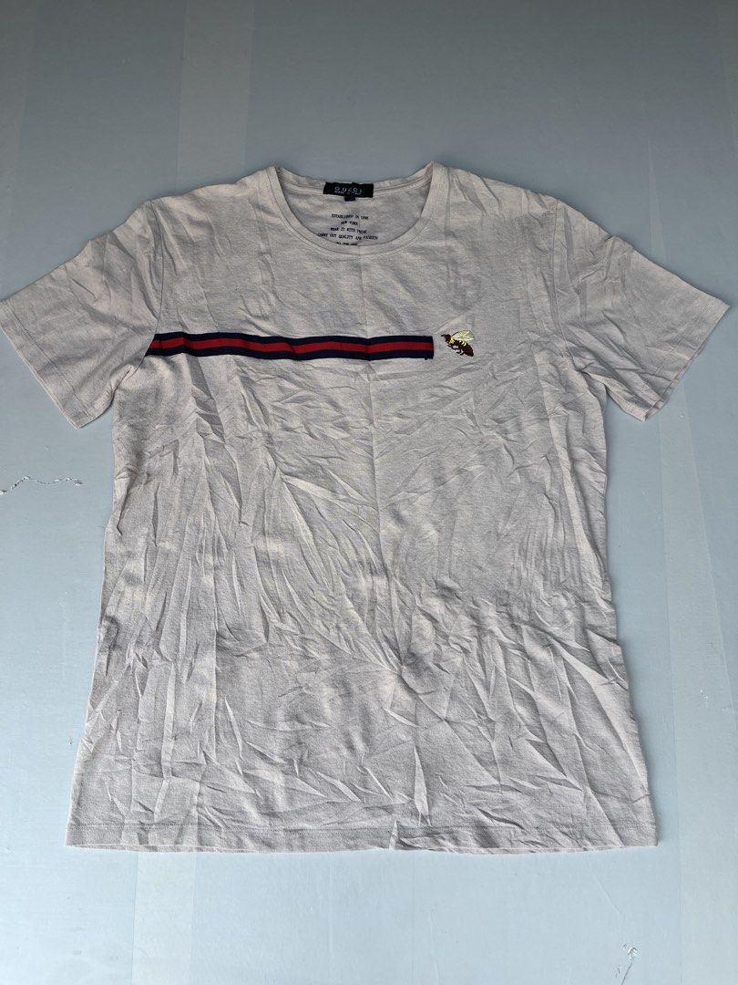 Gucci Bee Stripe T-shirt (Category: Luxury Apparel) located in Mabalacat. Submitted by aas_thriftfings (Listing ID 1434867074, Image 1). Description: - Authentic Gucci T-shirt - Size: 3XL - Made in Italy - Color: Light Beige - Design: Bee embroidery and red/navy chest stripe - Style: Crew neck - Condition: Excellent - Care instructions visible on tag.