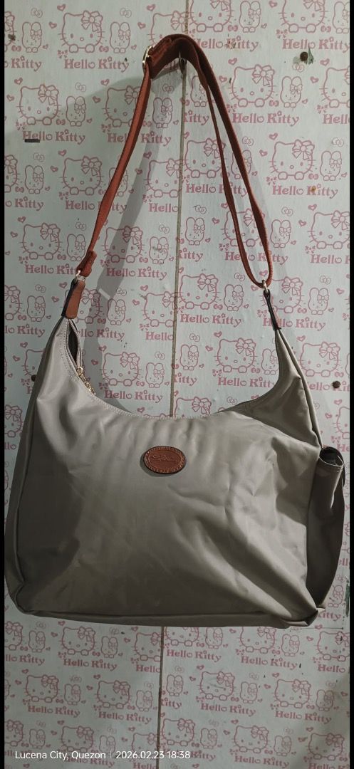 Longchamp Shoulder Bag (Category: Luxury Bags & Wallets) located in Manila. Submitted by _outofthecloset. (Listing ID 1434926573, Image 1). Description: - Authentic Longchamp shoulder bag - Beige nylon exterior with brown leather accents - Single shoulder strap - Front pocket with flap closure - White fabric interior lining - Includes Longchamp logo patch - Made in France - ISSUE MIN. SLICE .