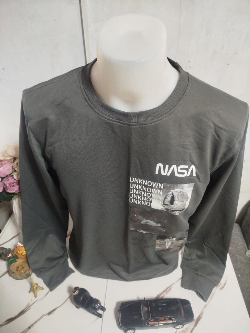 NASA Long Sleeve Shirt (Category: Tshirts & Polo Shirts ) located in Mandaluyong City. Submitted by allinthehood (Listing ID 1434887877, Image 2). Description: - Dark grey long sleeve shirt - Features a NASA logo - Graphic design on the front - Design includes the words "UNKNOWN" - Also includes "Dare to explore".