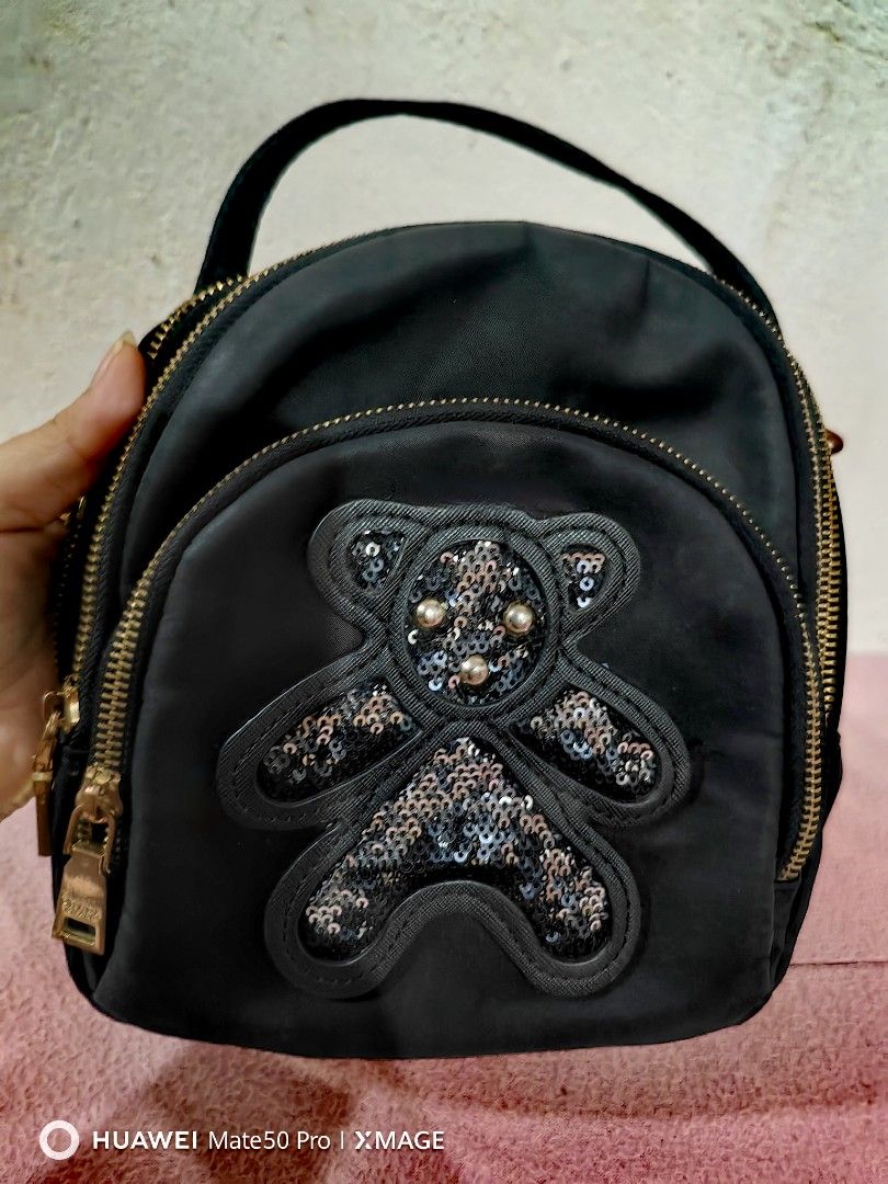 Prada Black Teddy Bear nylon Backpack (Category: Luxury Bags & Wallets) located in Villasis. Submitted by mysticforest.bb2b4b (Listing ID 1434895676, Image 1). Description: - Black backpack with teddy bear design - Multiple zippered compartments - Top handle - Detachable strap for shoulder or crossbody wear - Prada branded interior - Gold-toned zippers.