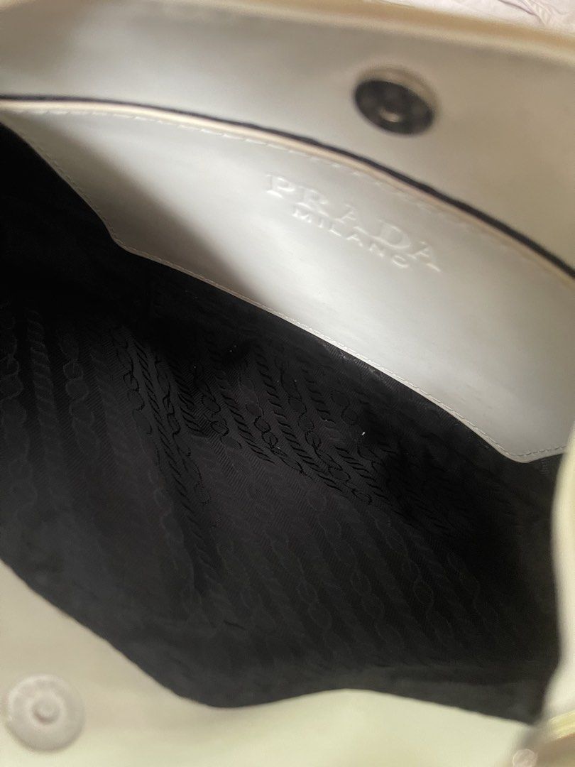 Prada White Shoulder Bag (Category: Luxury Bags & Wallets) located in San Pablo. Submitted by queenmomonline (Listing ID 1434893856, Image 2). Description: - Prada white shoulder bag - Curved design - Single shoulder strap - Prada logo on front - Black interior lining with Prada logo - Magnetic closure -Not auth -Needs cleaning.