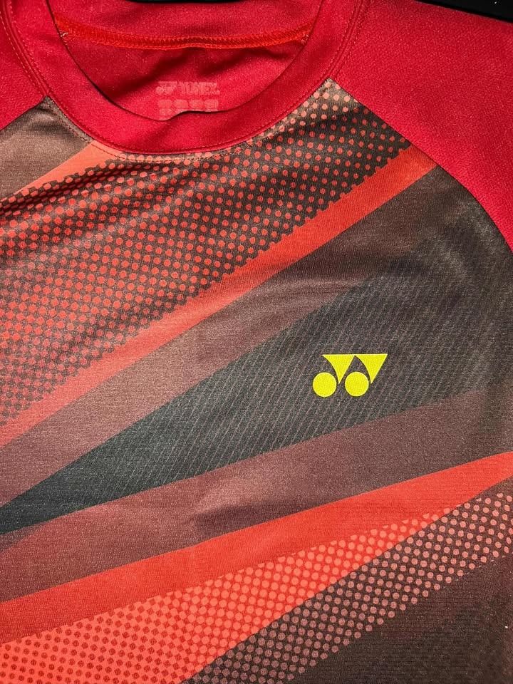 Yonex Badminton T-shirt (Category: Activewear) located in Manila. Submitted by okeanos (Listing ID 1434806760, Image 2). Description: ❤️🏸 Yonex Performance Tee 🏸❤️ Clean red / black sports performance tee featuring bold dynamic panel graphics with Yonex chest logo. Lightweight activewear piece perfect for badminton, gym, running, or casual sporty fits. 📏 Size: 19 x 27.5 (Fits Small) 🏷 UK Size: 36 🎨 Color: Red / Black 🧵 Material: 100% Polyes