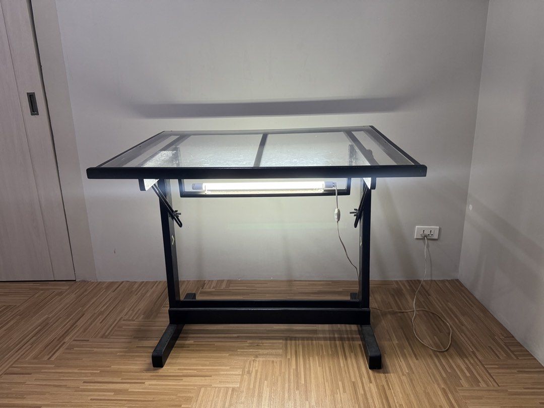 [PRELOVED] 40 inches by 30 inches Adjustable Drafting Table with Light (Category: Tables & Sets) located in Quezon City. Submitted by _aceys (Listing ID 1435138211, Image 2). Description: - 40 inches by 30 inches drafting table - Clear glass top - Black frame - Adjustable angle - Built-in light fixture with switch and cord - Sturdy base - Suitable for drawing and creative projects - Issue: Scratched acrylic top but won’t affect performance.