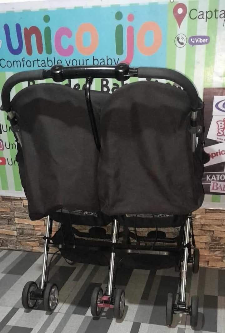 Double Stroller (Category: Strollers) located in Caloocan City. Submitted by Unicoijo02 (Listing ID 1435062669, Image 2). Description: - Black double stroller - Two seats with canopies - Foldable design - Multiple wheels for stability - Curved handle for comfortable pushing.