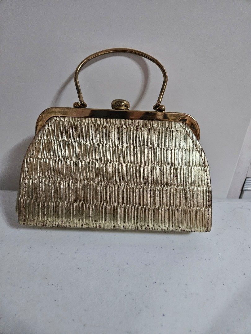 Gold Clutch Handbag with Handle (Category: Luxury Bags & Wallets) located in Caloocan City. Submitted by rm.diaz (Listing ID 1435087163, Image 1). Description: - Vintage gold clutch handbag - Gold clasp closure - Includes a gold chain - Black interior - Textured exterior - Curved, gold-toned metal handle.