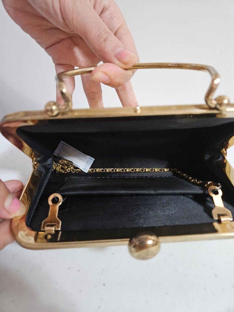 Gold Clutch Handbag with Handle (Category: Luxury Bags & Wallets) located in Caloocan City. Submitted by rm.diaz (Listing ID 1435087163, Image 2). Description: - Vintage gold clutch handbag - Gold clasp closure - Includes a gold chain - Black interior - Textured exterior - Curved, gold-toned metal handle.