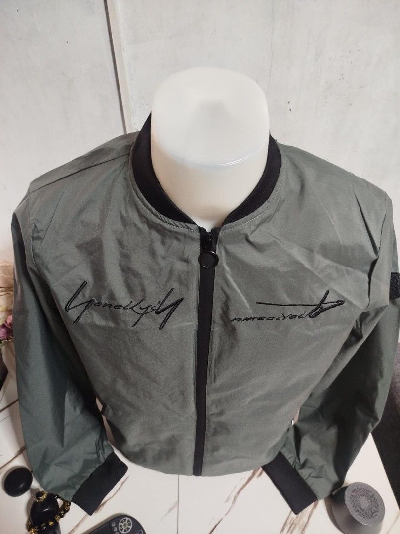 Men's Green Bomber Jacket (Category: Coats, Jackets and Outerwear) located in Mandaluyong City. Submitted by allinthehood (Listing ID 1435027433, Image 2). Description: - Stylish green bomber jacket for men - Black zipper and collar - Embroidered text detail - Printed inner lining - Convenient left sleeve pocket - Ideal for casual outfits.