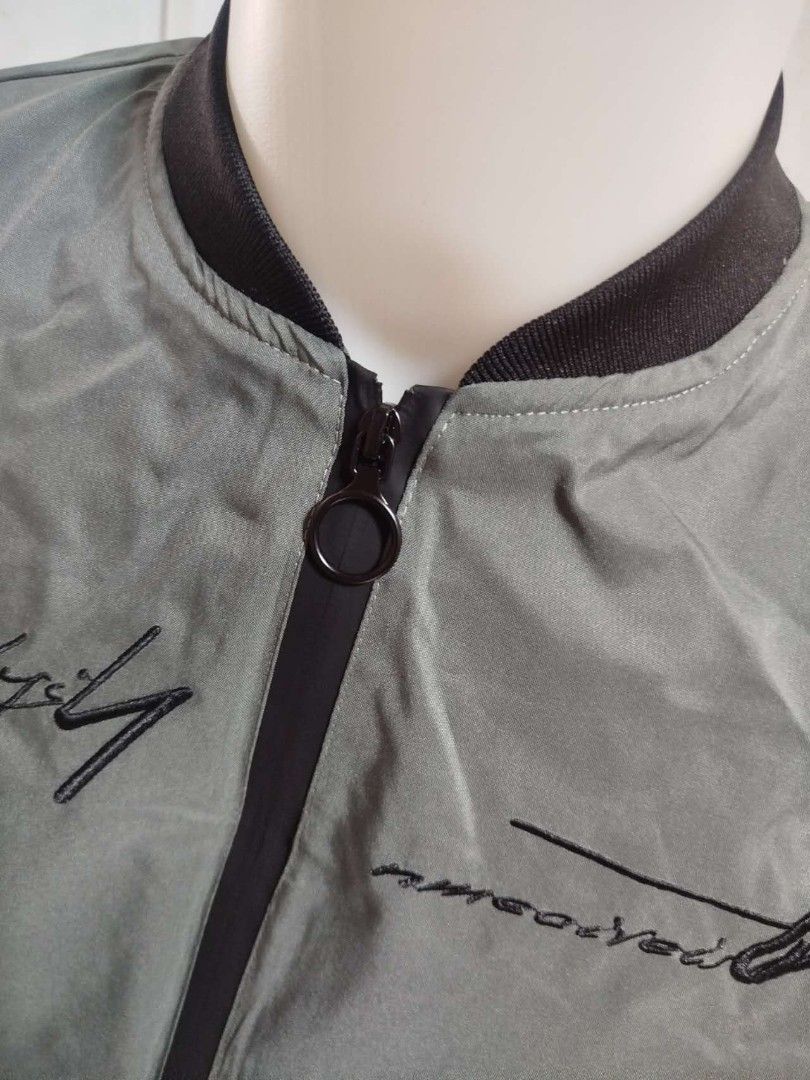 Men's Green Bomber Jacket (Category: Coats, Jackets and Outerwear) located in Mandaluyong City. Submitted by allinthehood (Listing ID 1435027433, Image 3). Description: - Stylish green bomber jacket for men - Black zipper and collar - Embroidered text detail - Printed inner lining - Convenient left sleeve pocket - Ideal for casual outfits.