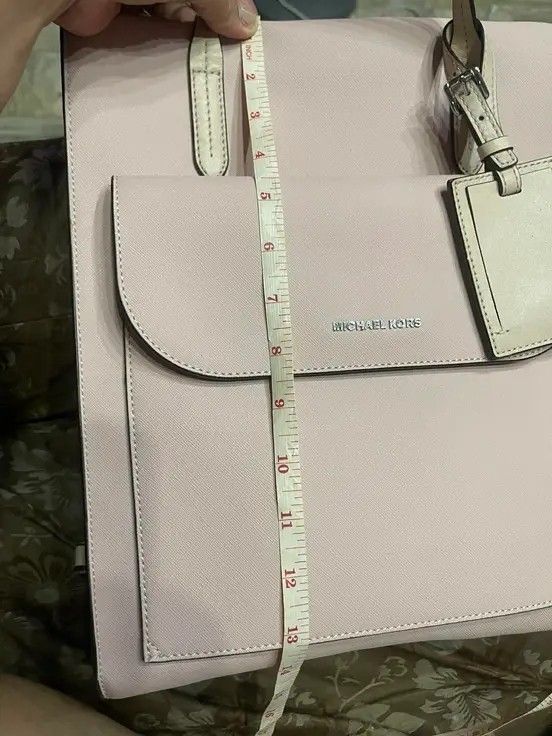 Michael Kors Saffiano leather backpack (Category: Luxury Bags & Wallets) located in Bulacan. Submitted by alfredcarp0905 (Listing ID 1435162703, Image 3). Description: - Authentic Michael Kors tote bag - Color: Light Pink - Features: - Front pocket - Luggage tag - Two top handles - Shoulder strap - Height: Approximately 12 inches - Michael Kors logo on front.