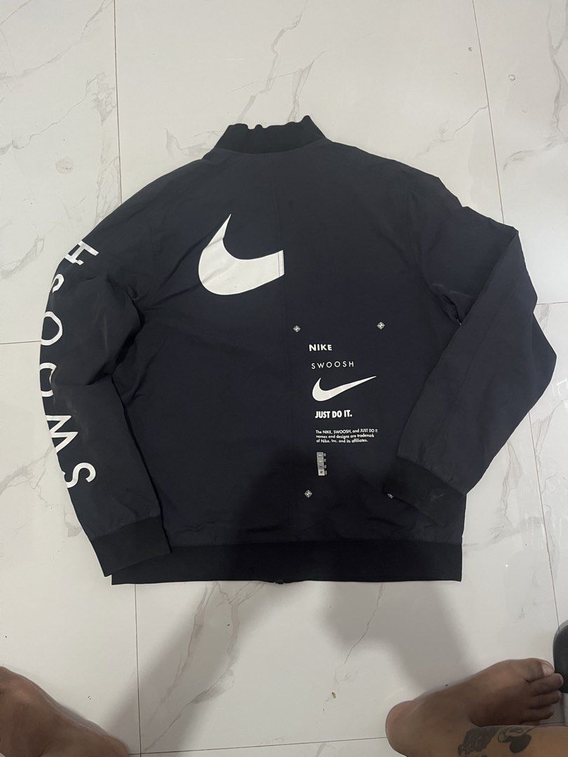 Nike Swoosh Bomber Jacket - Black - Size L (Category: Coats, Jackets and Outerwear) located in Manila. Submitted by madebyph (Listing ID 1435125291, Image 2). Description: Black Nike bomber jacket with white Swoosh logo and "SWOOSH" printed on the sleeves. Features a full-zip closure and a ribbed collar and cuffs. The back of the jacket has a large Swoosh logo and "NIKE SWOOSH JUST DO IT" printed. Made in Vietnam. Size L..