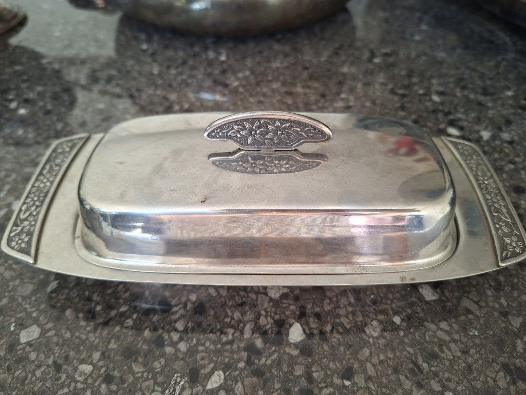 Silver Butter Dish with Lid (Category: Food Organization & Storage) located in Calamba. Submitted by mariacarme86067 (Listing ID 1435170348, Image 2). Description: Elegant silver butter dish with a matching lid. Features a rectangular shape with decorative floral accents on the lid handle and the dish's edges. The dish is designed to hold butter and keep it fresh. A separate silver gravy boat is also available. Both are vintage Japan stainless st